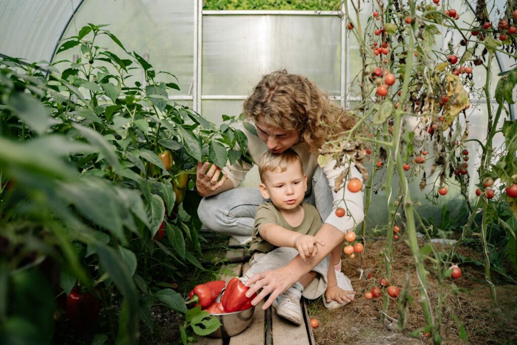 Mother and Child Gathering Vegetables in Greenhouse